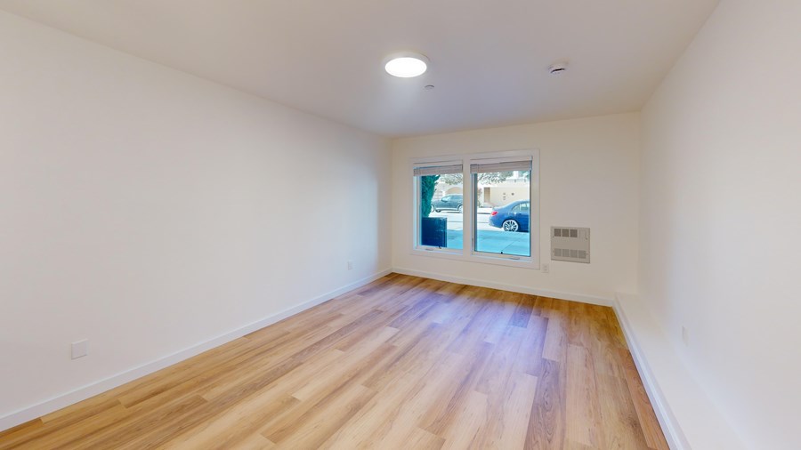 A room with wooden flooring and a window showing a street view.